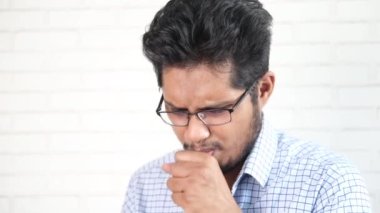  Genç Asyalı adam öksürüyor ve hapşırıyor. 