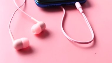 Boş ekranlı akıllı telefon, pembe arka planda kulaklık. 