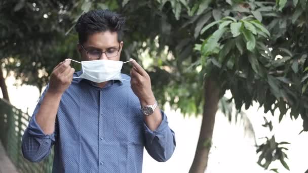 Jovem asiático homem colocando cirúrgico rosto máscara ao ar livre — Vídeo de Stock