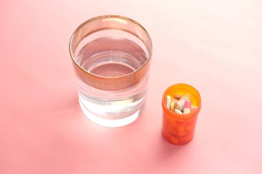  Tıbbi hap kutusu ve pembe üzerine bir bardak su. 