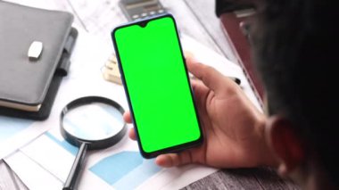 Ofis masasında akıllı telefon kullanan bir adamın dikiz görüntüsü 