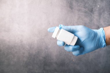 Doktor, koruyucu eldivenlerle siyah hapları tutuyor. 