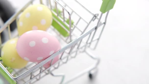 Easter concept with egg in a shopping cart and a clock on background. — Stock Video