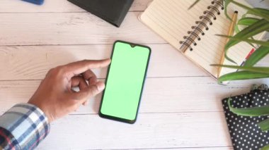 Ofis masasında akıllı telefon kullanan bir adamın üst görüntüsü. 