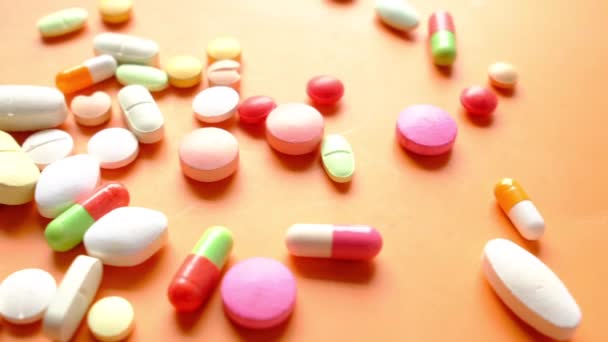 Närbild av många färgglada piller och kapslar på orange bakgrund — Stockvideo