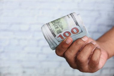 Bir adamın eli 100 dolar nakit sayıyor. 