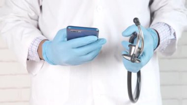 Beyaz önlüklü doktor akıllı telefon kullanıyor..