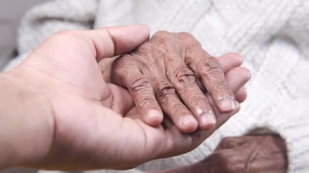 Detail záběr mladého muže držící ruku seniorských žen — Stock video