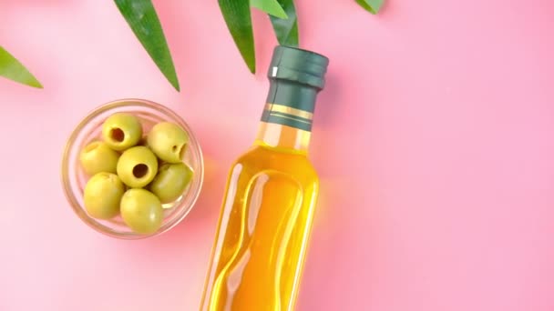 Bottiglia di olio d'oliva e olive fresche in un contenitore su rosa . — Video Stock