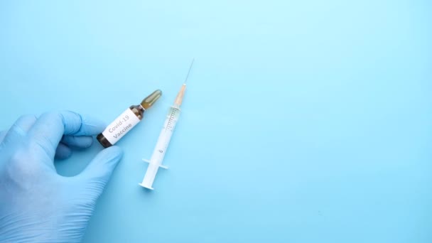 Ručně v latexových rukavicích, skleněné ampulové vakcíně a injekční stříkačce na stole — Stock video