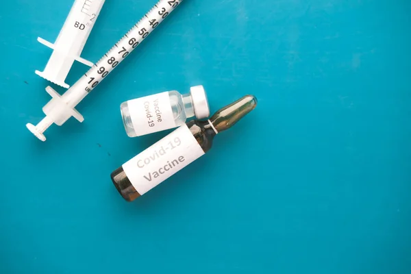 Close up da vacina contra o coronavírus e seringa sobre fundo verde claro — Fotografia de Stock