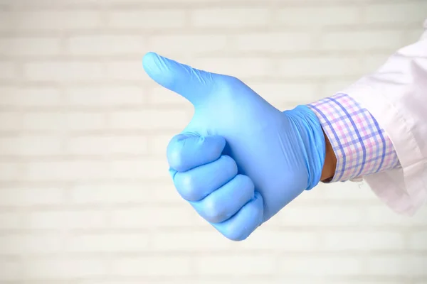 Hand in medical gloves showing a thumb-up on white background — Stock Photo, Image