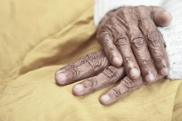 Close up of hand of a elderly person on yellow — Stock Photo, Image