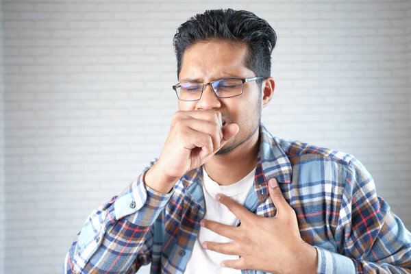  young sick man coughing and sneezes 