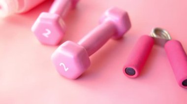  Pembe halterler, egzersiz paspası ve pembe arka planda su şişesi. 
