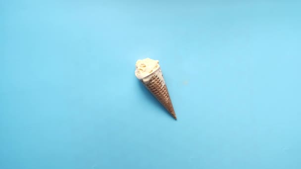 Sorvete de baunilha em cone em fundo azul vista superior — Vídeo de Stock