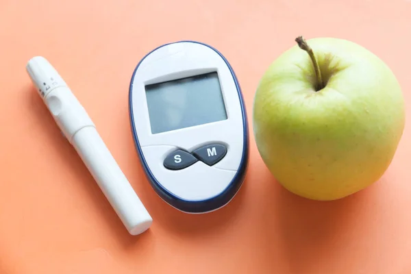 diabetic measurement tools, apple on orange background