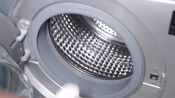 Genç adam çamaşır makinesine havlu koyuyor.. — Stok video