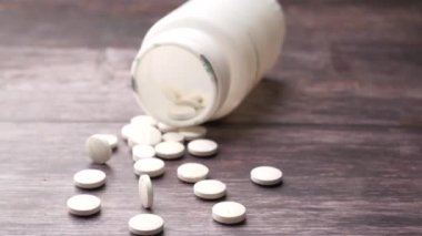 Masaya beyaz renkli tıbbi haplar dökülüyor. 