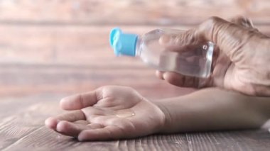 Yaşlı kadınlar çocuk eline dezenfektan sürerler.