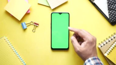 Sarı arka planda akıllı telefon kullanan bir adamın üst görünümü 