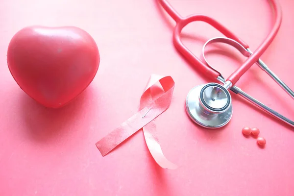 Red ribbon HIV, and stethoscope on red background. — Stock Photo, Image
