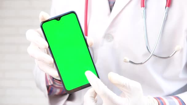 의사들 이 스마트 폰을 녹색 화면으로 들고 보호 장갑을 끼고 있는 모습 — 비디오