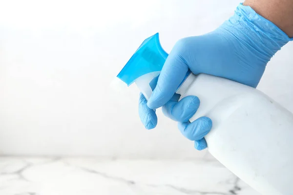 Mano en guantes de goma azul que sostiene la botella del aerosol con espacio de copia —  Fotos de Stock