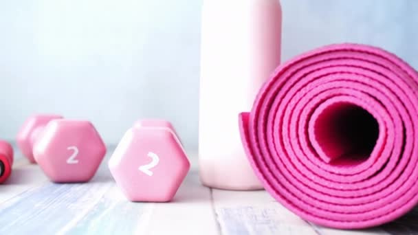 Rózsaszín színű súlyzó, gyakorló szőnyeg és vizes palack fa háttér — Stock videók