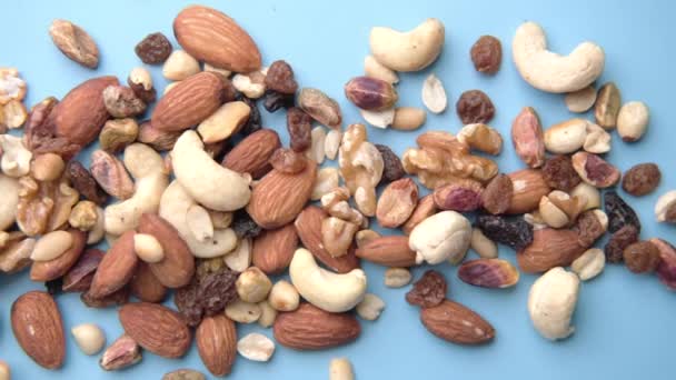 Gros plan de nombreuses noix mélangées sur fond bleu — Video