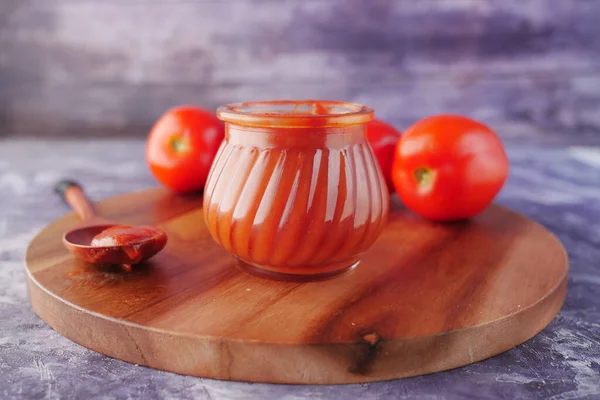 Tomato sauce in a small jar with fresh tomato on table — Stock Photo, Image