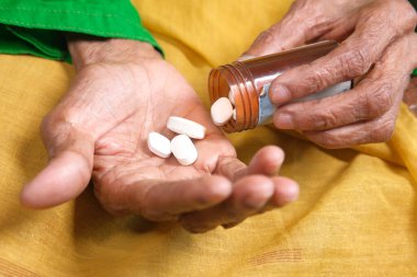 Yaşlı kadınlar bir konteynırdan ilaç alıyor. 