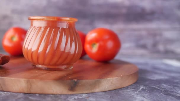 Томатный соус в маленькой банке со свежими помидорами на столе — стоковое видео