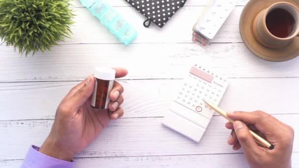 Personne main tenant le récipient de pilule et analysant la date sur le calendrier — Video