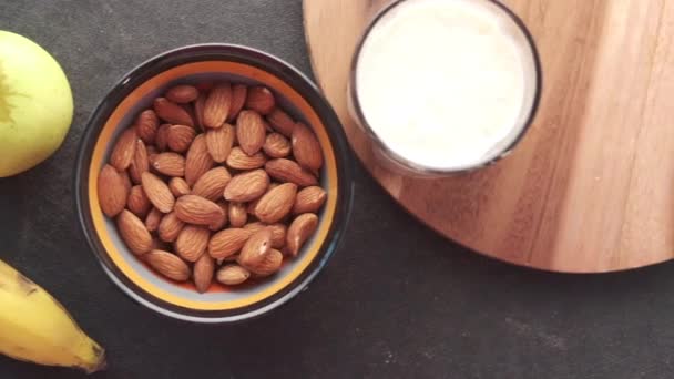 Nuez de almendra, plátano, manzana y leche en la mesa — Vídeos de Stock