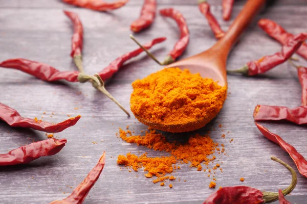 Chili powder and dried peppers on table background.