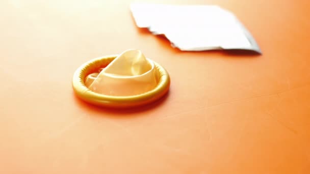 Primer plano del condón sobre fondo naranja — Vídeos de Stock