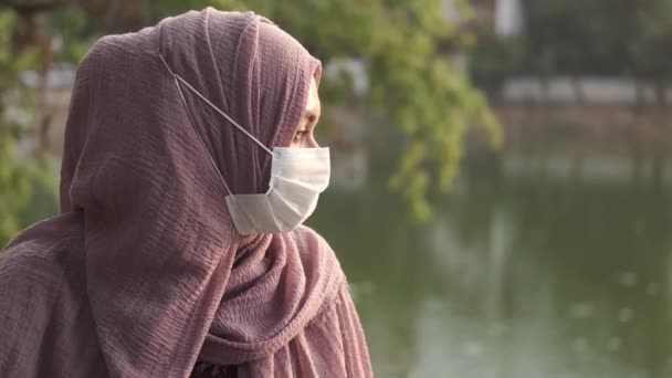 Vista lateral da mulher muçulmana com máscara de gripe no parque — Vídeo de Stock