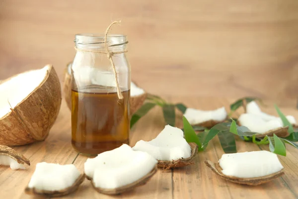 Parte de coco fresco e garrafa de óleo em uma mesa — Fotografia de Stock