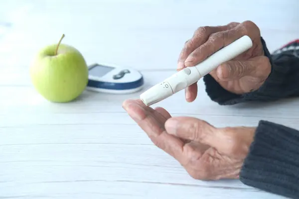 Äldre kvinnor med diabetes mäter glukosnivån i hemmet — Stockfoto