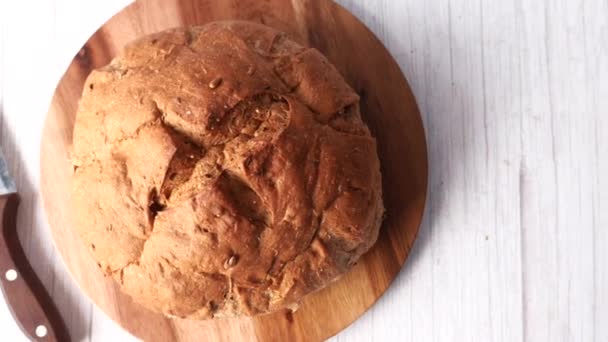 Yuvarlak kahverengi ekmeğin doğrama tahtasındaki üst görüntüsü — Stok video