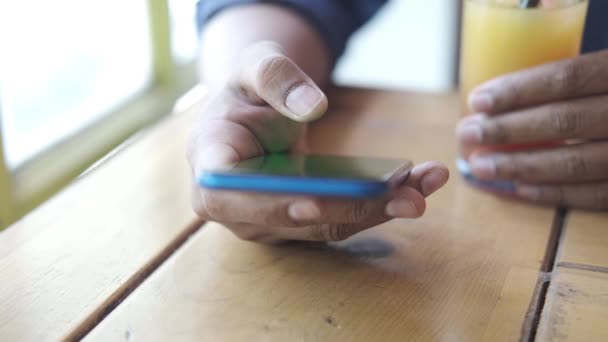 Primer plano de la mano del hombre joven usando el teléfono inteligente y beber jugo de naranja — Vídeos de Stock