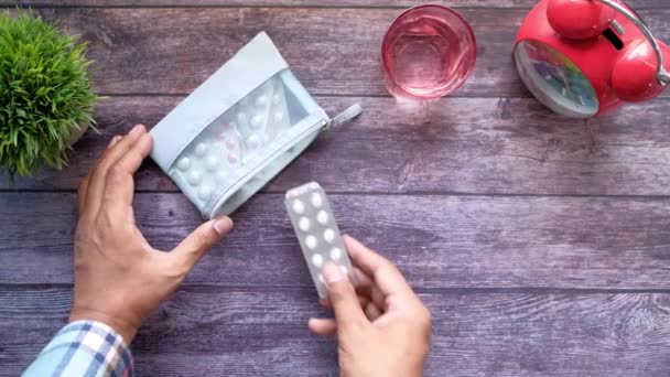 Joven hombre poniendo píldoras de blister paquete en s pequeña bolsa — Vídeos de Stock