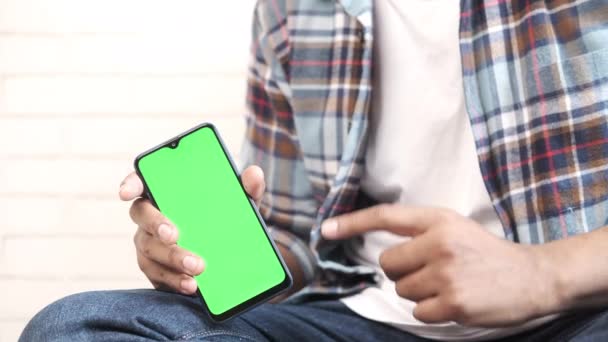 Nahaufnahme der Hand eines jungen Mannes mit Smartphone mit grünem Bildschirm — Stockvideo