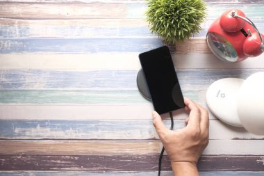 Kablosuz şarj pedi kullanarak akıllı telefon şarj ediliyor, üst görünüm 