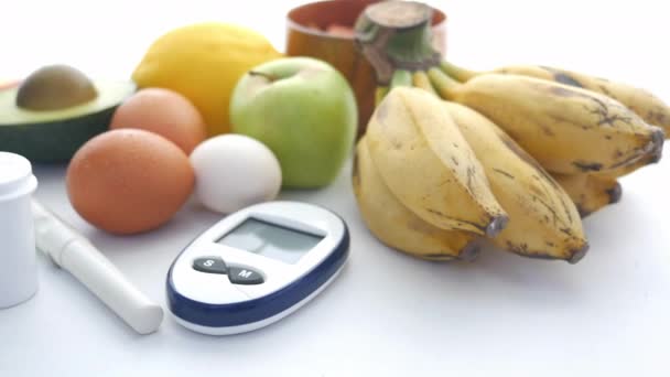 Κλείσιμο διαβητικών εργαλείων μέτρησης και νωπών φρούτων σε λευκό φόντο — Αρχείο Βίντεο