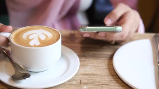 Ženy ruka drží chytrý telefon a pití kávy — Stock video