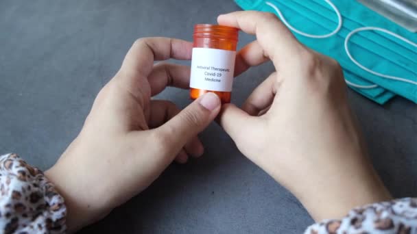 Donne mano tenendo covid 19 pillole mediche e maschere chirurgiche blu sul tavolo — Video Stock