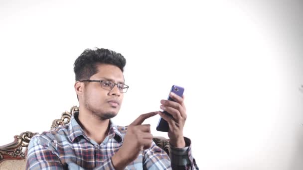 Trauriger junger Mann sitzt mit Smartphone auf Sofa. — Stockvideo