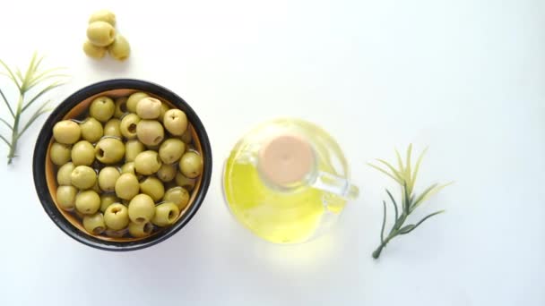 Botella de aceite de oliva y oliva fresca en un recipiente sobre blanco . — Vídeo de stock